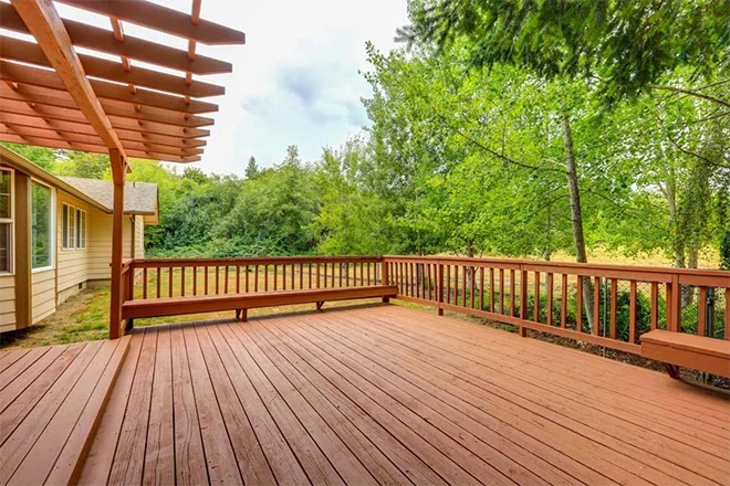 Beautiful reddish-brown deck with built-in seating and a pergola