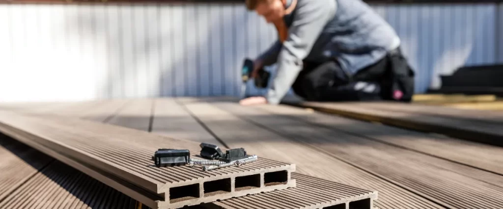 a person laying composite decking boards during a deck construction project