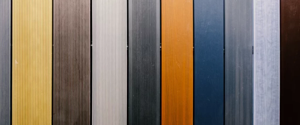 Deckorators vs. Trex: Which Deck Material Wins in 2026? 2 samples of composite decking boards in various colors and finishes
