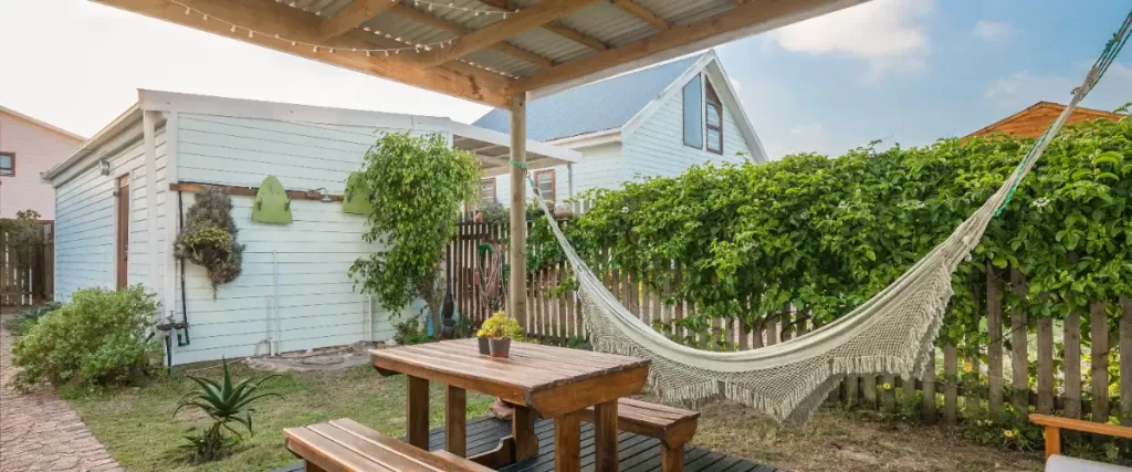 26 Covered Deck Ideas to Transform Your Outdoor Space 2 a cozy covered deck with a wooden picnic table and a hammock