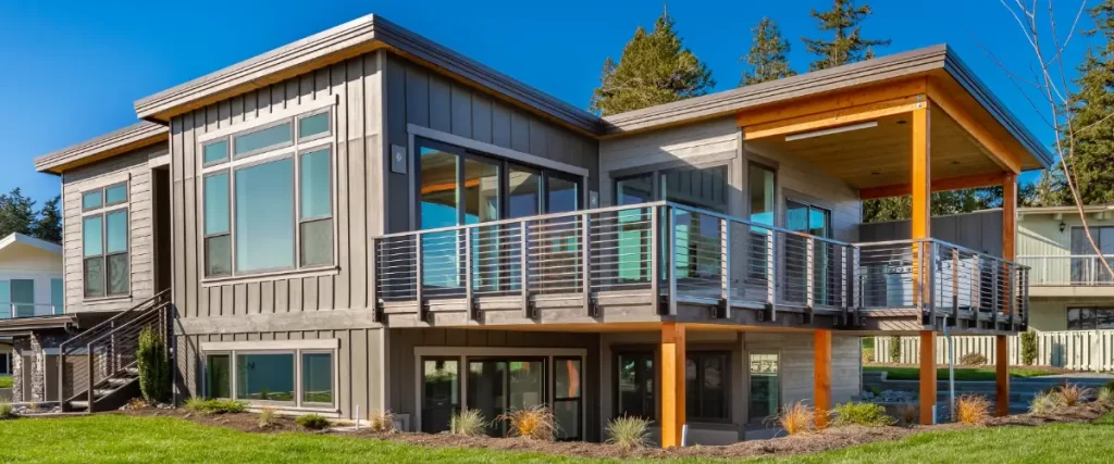 a modern, two-story house featuring a large outdoor deck with horizontal deck railings made of cable material