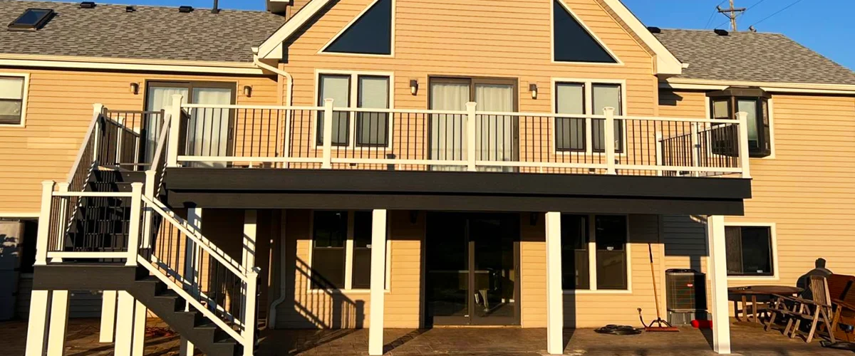NADRA Certified Deck Safety Inspection 13 Elevated composite deck with white and black railings on tan house featuring walk-out basement and staircase - on page