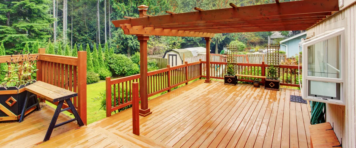 Modern deck with pergola and wooden railing in a lush backyard