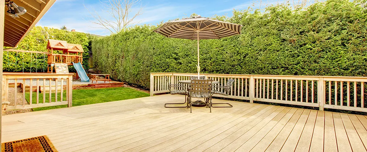Backyard deck with umbrella-shaded dining set and play area nearby
