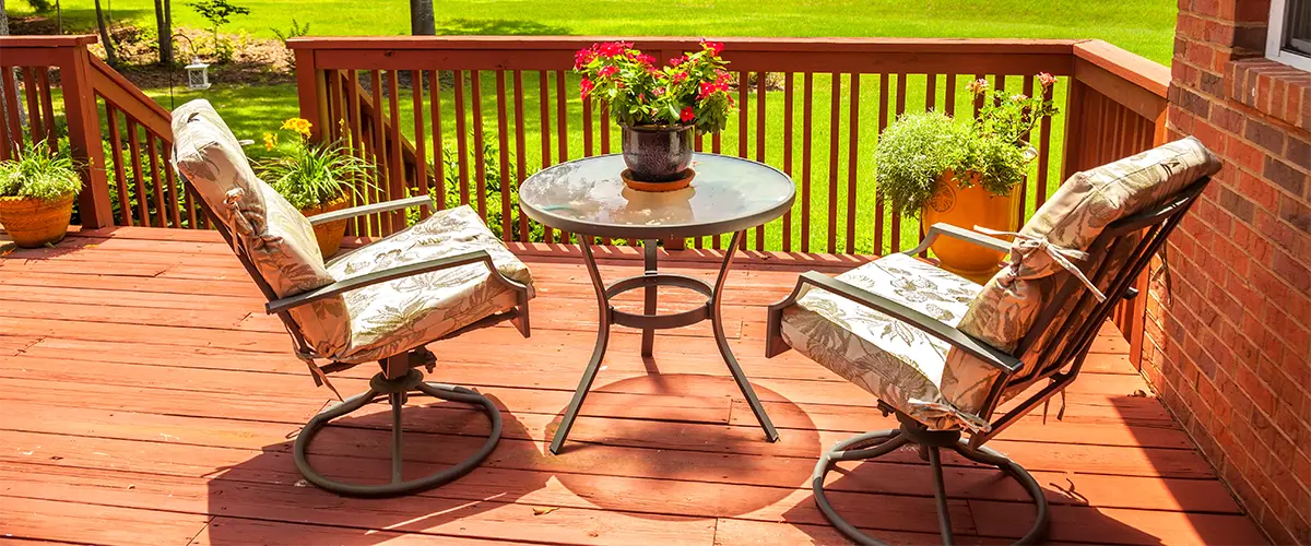 Cozy redwood deck with round table and two cushioned chairs