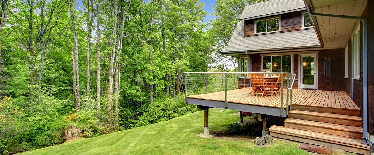Deck Repair in Roscoe, IL 8 Wooden deck with dining set and cable railing in forested backyard