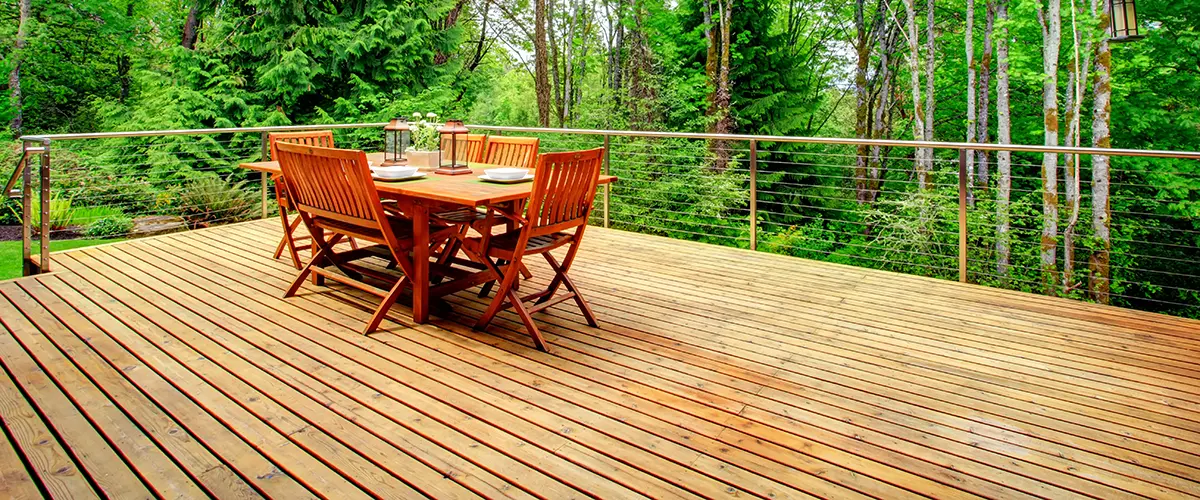 Deck Repair in Roscoe, IL 2 Wooden deck with dining set and cable railing in forested backyard