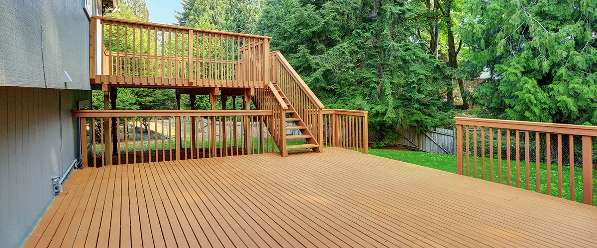 Deck Restoration in Rockford, IL 2 c8 op image large wooden deck with staircase and railings in a backyard surrounded by trees