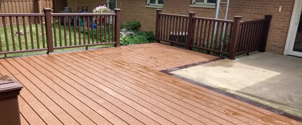 Brown composite decking with railing attached to a brick house