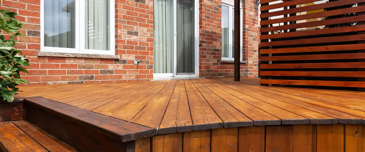 Backyard deck with natural wood finish attached to brick house