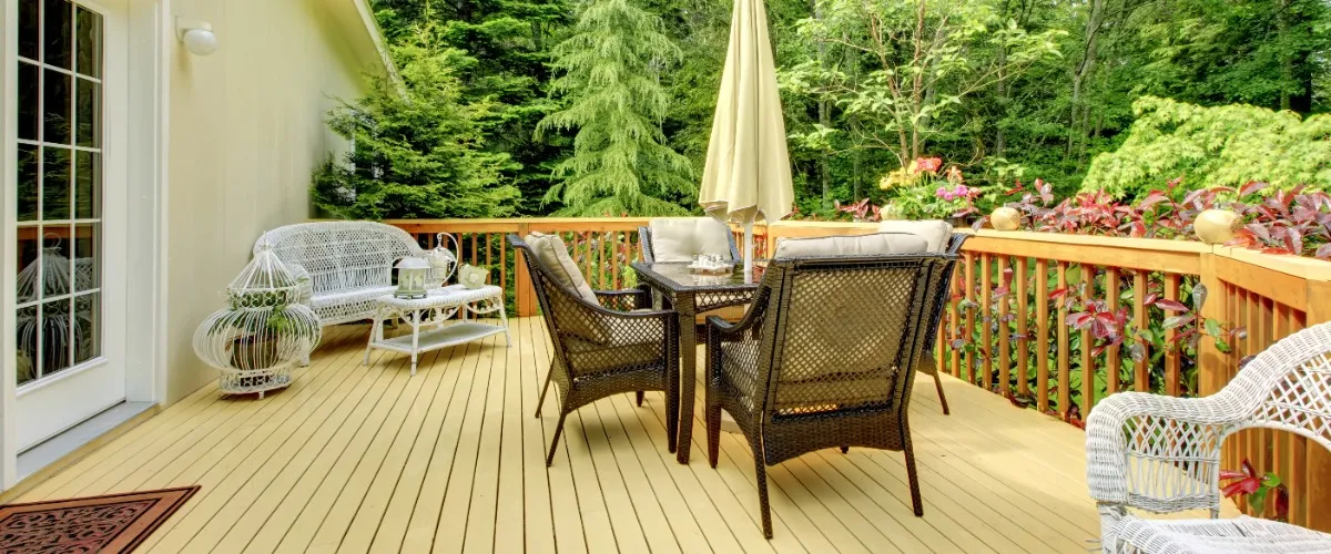 A cozy deck featuring wicker chairs and a large umbrella for shade