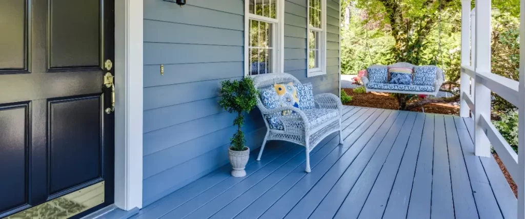 A porch with blue composite decking featuring a cozy swing