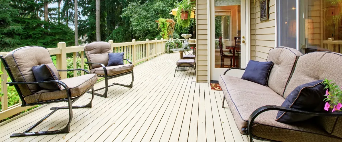A wooden deck featuring several chairs and a table, set for outdoor relaxation or dining