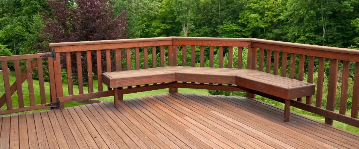 an elevated outdoor wooden deck with a built-in bench and railing