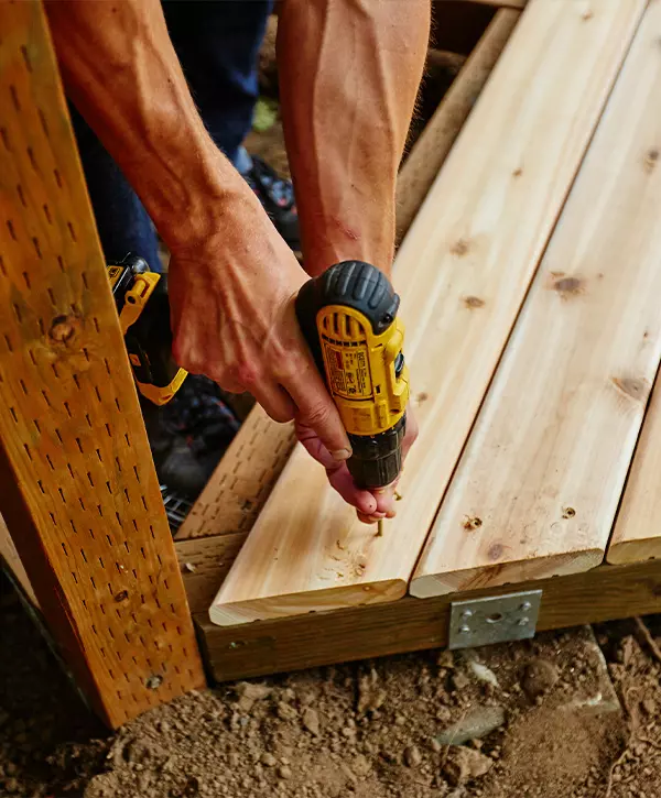 Close up of a technician using a power drill to secure wood planks during a deck restoration project in Loves Park, IL.