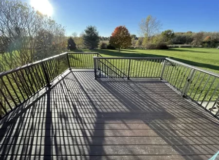 Spacious metal railing deck overlooking a large backyard with scenic open landscape and autumn trees